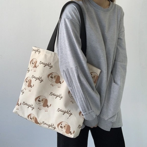 Dettaglio della borsa tote in tela beige con motivo cane e tracolle nere