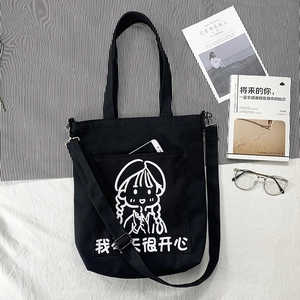 Close-up of black canvas bag front pocket holding a smartphone with cartoon illustration