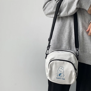 Detail of white canvas crossbody bag with cute rabbit illustration and adjustable strap