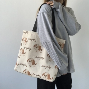 Dettaglio della borsa tote in tela beige con stampa cane indossata da modella su grigio