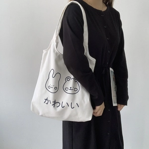 Detail of white canvas tote bag featuring cute cartoon rabbit and frog illustrations