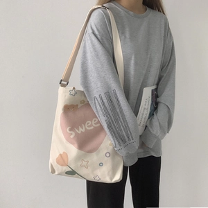 Détail d'un sac bandoulière en toile avec motif ours et cœur et sangle ajustable