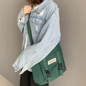 Detail view of the forest green nylon messenger bag with double buckles and logo tag