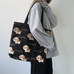 Dettaglio della borsa tote in tela nera con motivo di cane indossata da una modella