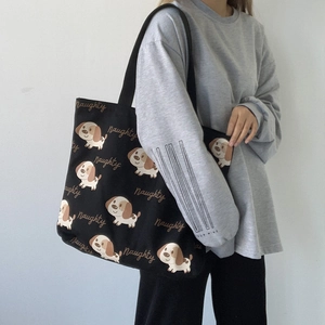 Dettaglio della borsa tote in tela nera con stampe di cuccioli indossata da modella