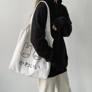 Detail of white canvas tote bag featuring cute cartoon rabbit prints and Japanese text