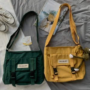 Detail of green and yellow nylon messenger bags with buckle pockets and brand label
