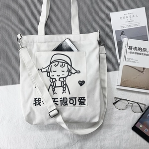 Detail of white canvas tote bag featuring cute cartoon girl print and front pocket for phone