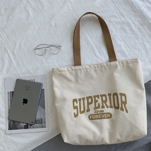 Detail of off-white canvas tote bag with brown straps and Superior retro lettering print