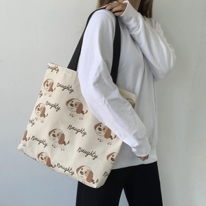 Dettaglio della borsa tote in tela con stampa cucciolo e tracolla nera su modella