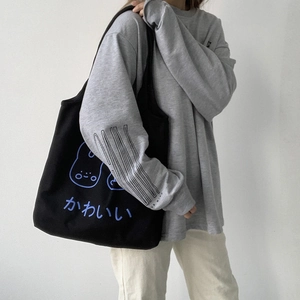 Close-up of black canvas tote bag featuring cute blue cartoon design and Japanese text
