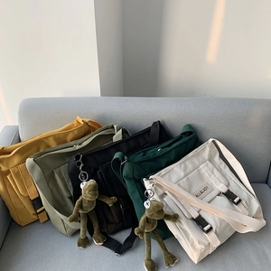 Collection of multi-color canvas messenger bags with cute frog charms on a grey sofa