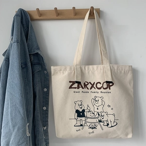 Detail of canvas tote bag with ZARXCOP graphic print hanging on a wooden hook