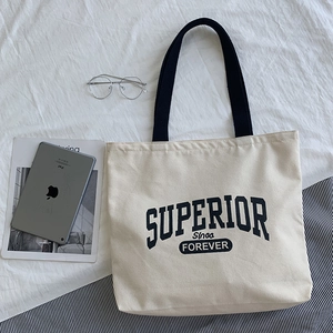 Detail of off-white canvas tote bag with black straps and vintage letter print