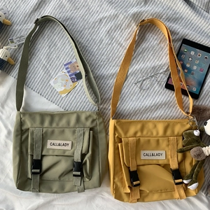 Flat lay of canvas messenger bags in green and yellow with cute frog pendant detail