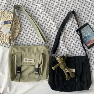 Detailed flat lay of green and black nylon messenger bags with buckles and strap