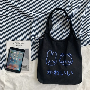 Detail of black canvas tote bag featuring cute cartoon rabbit and bear illustration