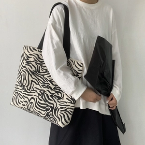 Détail du sac cabas en toile à motif zèbre avec de larges bandoulières noires résistantes