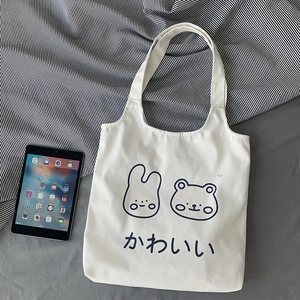 Detail of white canvas tote bag featuring cute cartoon rabbit and bear illustration