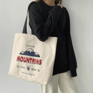 Detail view of canvas tote bag with blue mountain print and red mountains lettering