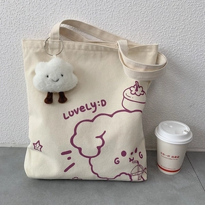 Close-up of canvas tote bag with purple cartoon print and plush cloud charm accessory