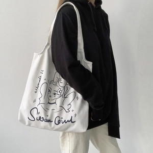 Vista laterale della borsa tote in tela bianca con illustrazione portata da una modella