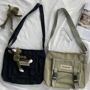 Detail of nylon messenger bags in black and olive green with frog pendant charms