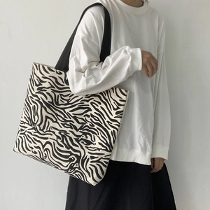 Gros plan du sac cabas en toile à motif zèbre porté par un mannequin féminin