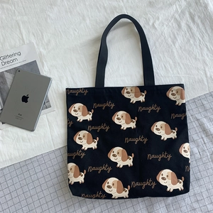 Dettaglio della borsa tote in tela nera con stampe di cani e scritta Naughty ricamata