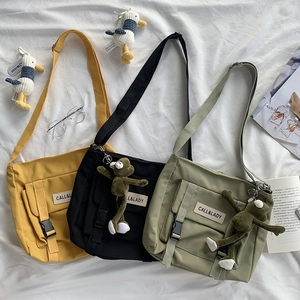 Detailed view of yellow, black, and olive nylon messenger bags with frog charms