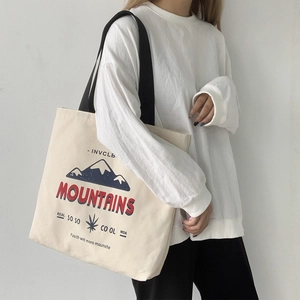 Detail of canvas tote bag featuring blue mountain print and wide black shoulder strap