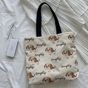 Dettaglio della borsa tote in tela con motivi di cani marroni e scritta Naughty