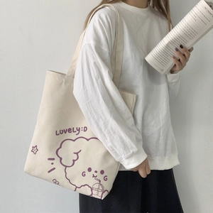 Detail of off-white canvas tote bag featuring a purple cartoon dog and Lovely:D print