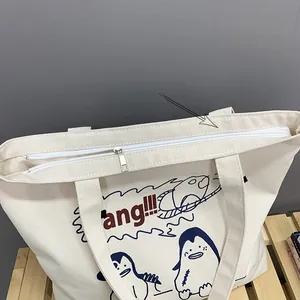 Detail of reinforced shoulder strap and metal zipper on cream canvas tote bag