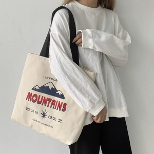Minimalist beige canvas tote bag with mountain print and black shoulder straps