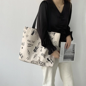 Détail du sac cabas en toile blanc cassé avec graffitis rock et bandoulière noire