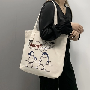 Detail of a large canvas tote bag with a cute cartoon penguin print and comfortable wide strap