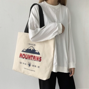 Close-up of cream canvas tote bag with mountain print and wide black shoulder straps
