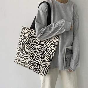 Détail d'un sac cabas en toile à motif zèbre avec larges bretelles noires et grande capacité interne