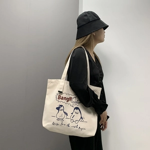 Detail of white canvas tote bag with blue penguin print and large capacity design