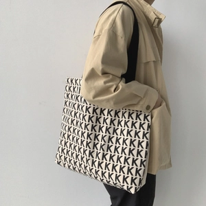 Grande borsa tote in tela beige con motivo a lettere K nere e tracolla larga