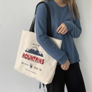 Minimalist canvas tote bag with mountain print and black handles for daily commuting