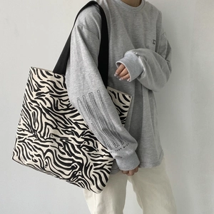 Vue latérale du grand sac cabas en toile à motif zèbre porté à l'épaule sur modèle