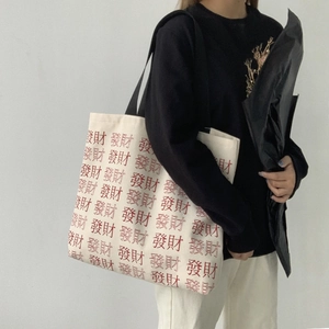 Detail of canvas tote bag with red Chinese fortune text and black shoulder strap