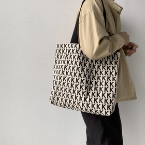 Dettaglio di una grande borsa tote in tela con motivo ripetitivo di lettere K in bianco e nero