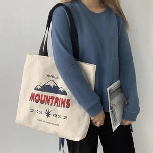 Detail view of the mountain print and INVCLB logo on a durable white canvas tote bag