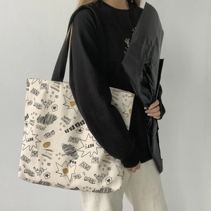 Detail of off-white canvas tote bag featuring black comic graffiti and roar print