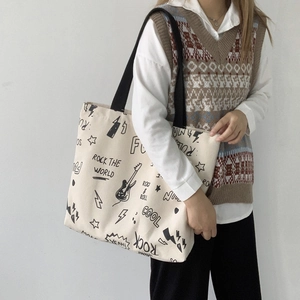 Grand sac cabas en toile beige avec graffitis rock porté par un mannequin de profil