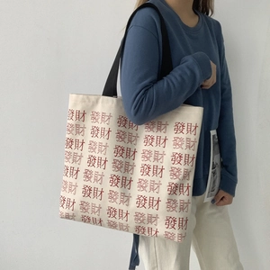 Detail of large canvas tote bag with red Chinese character print and black shoulder strap