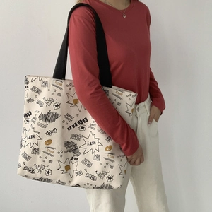 Detail of canvas tote bag featuring comic style graphic prints and black shoulder strap